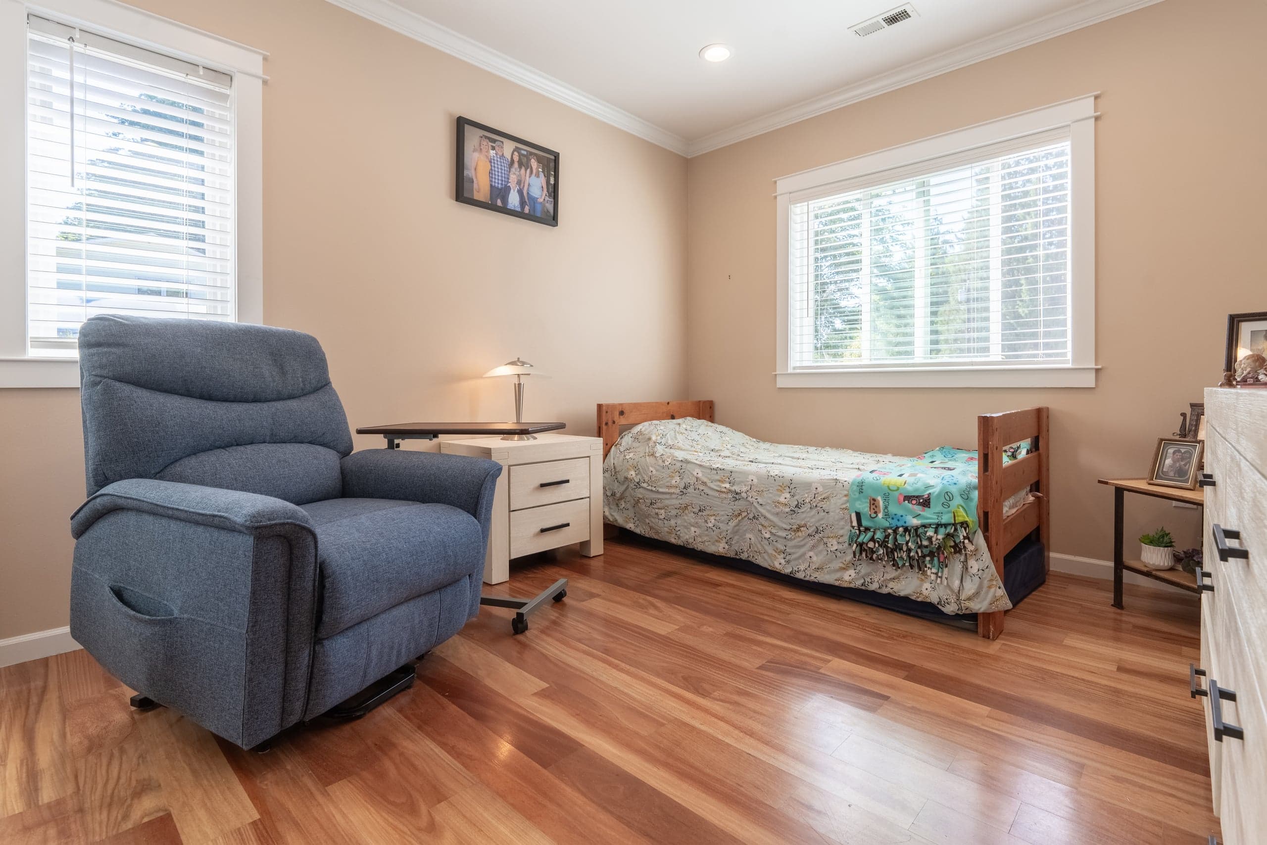 A private bedroom with cherry hardwood floors and a large window.